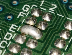 Solder Bridging Defects on PCB - Bigmate Philippines Inc. Close-up of a PCB showing solder bridging between adjacent pads, causing unintended connections.